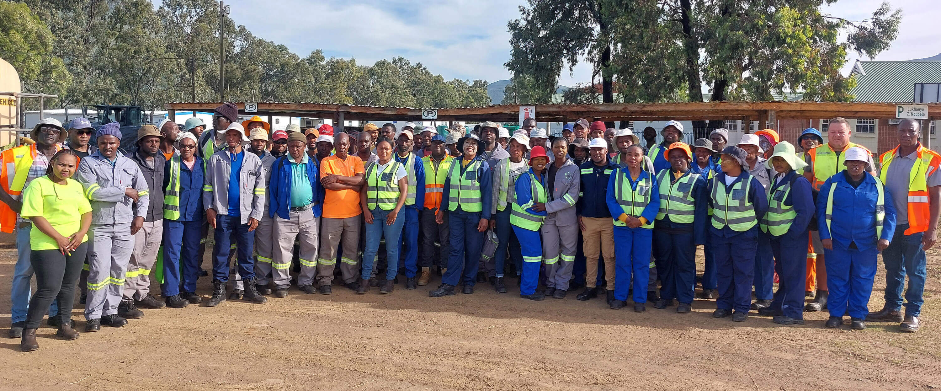 A diverse group of individuals in work attire smiling together for a group photo, showcasing teamwork and camaraderie.