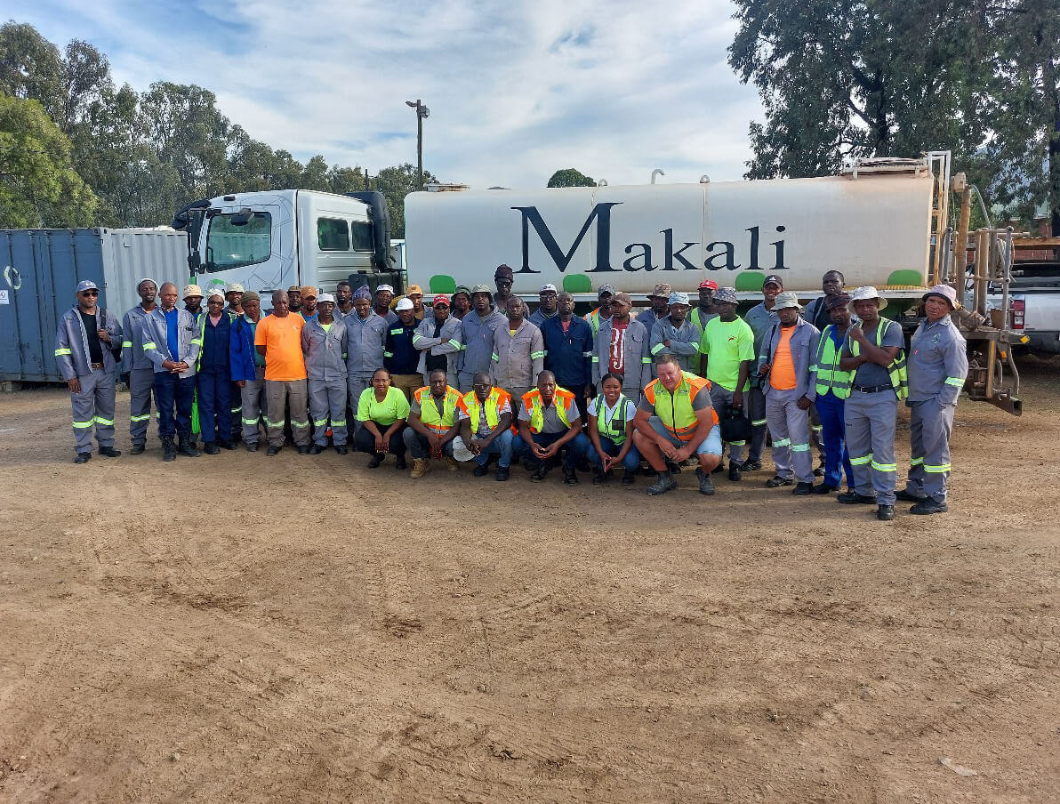  A diverse group of individuals wearing orange and yellow safety gear, standing together in a professional setting.